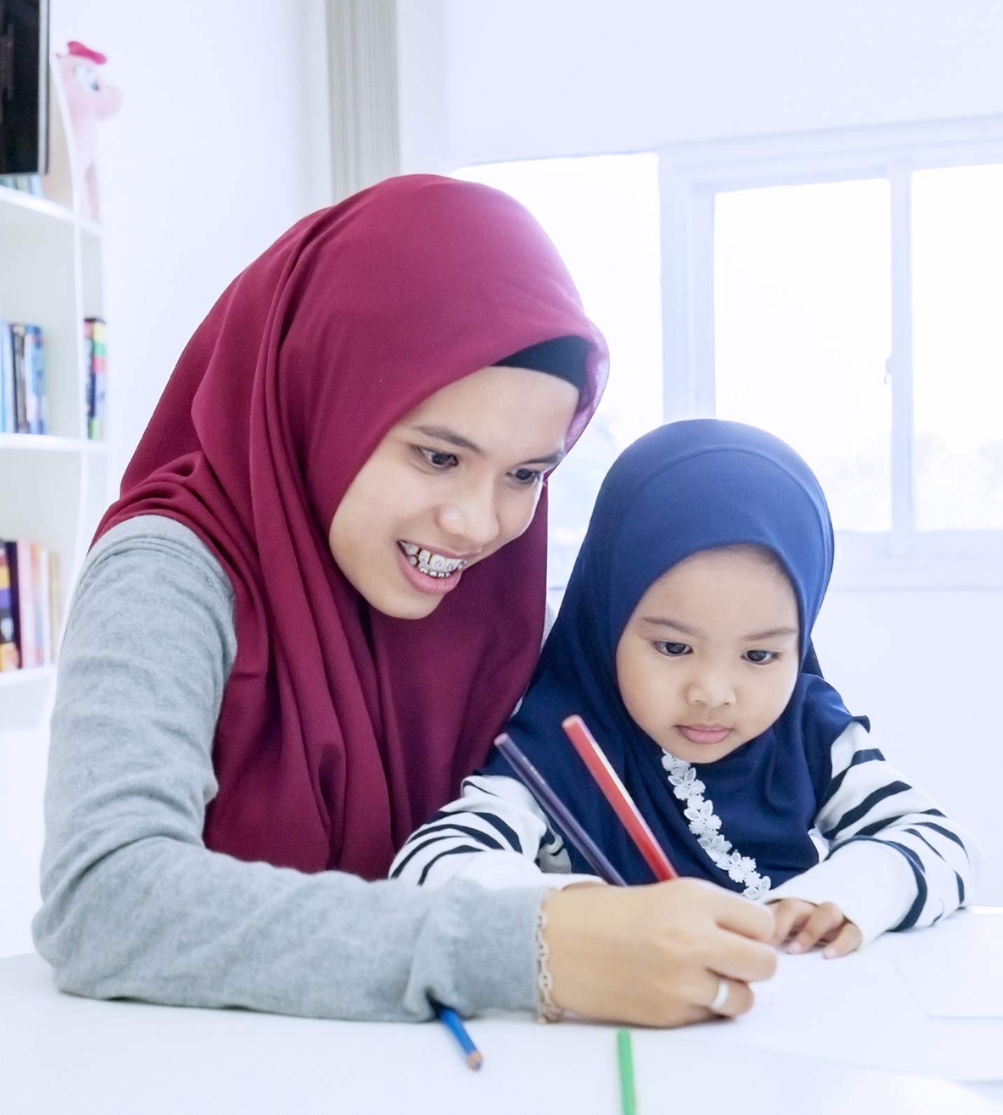 Mother teaching her daughter to write on a book